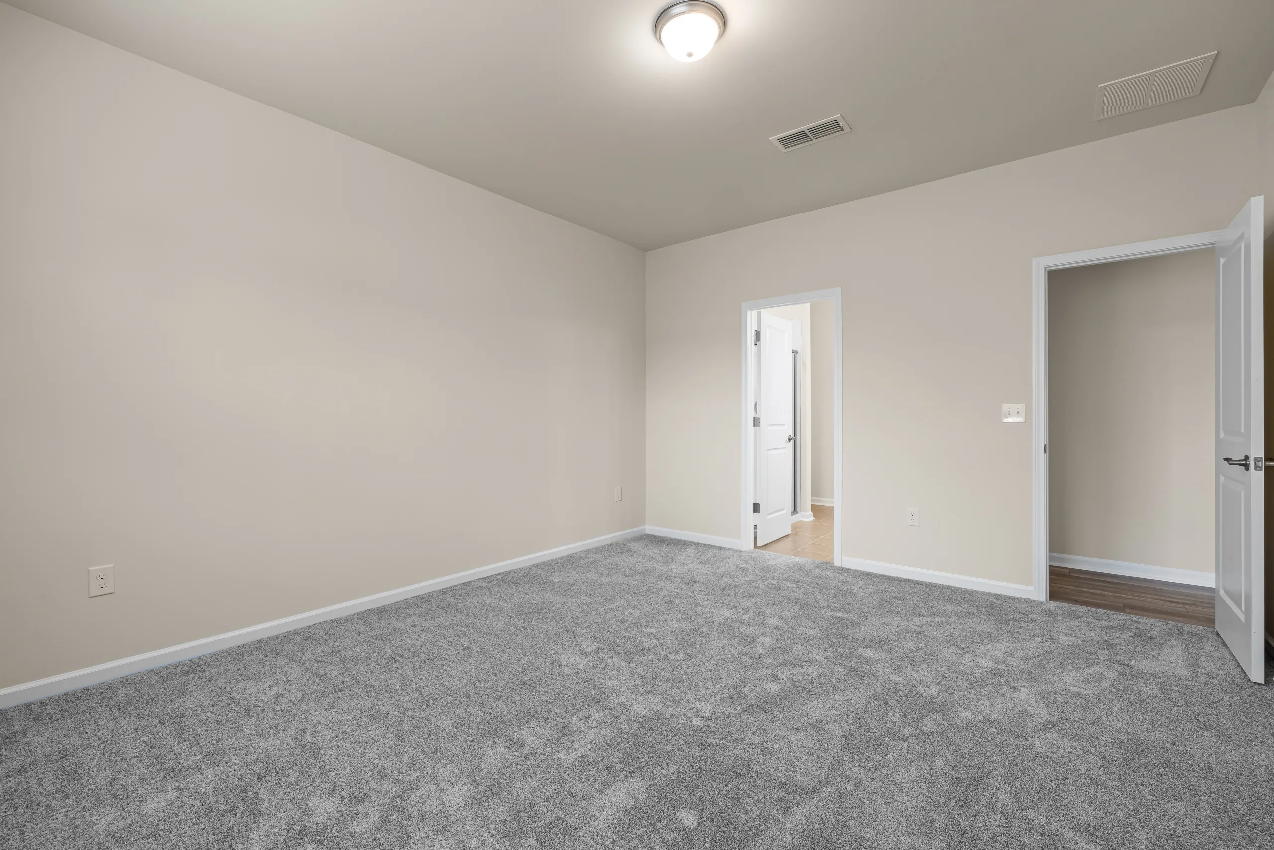An empty room with a carpet and white walls