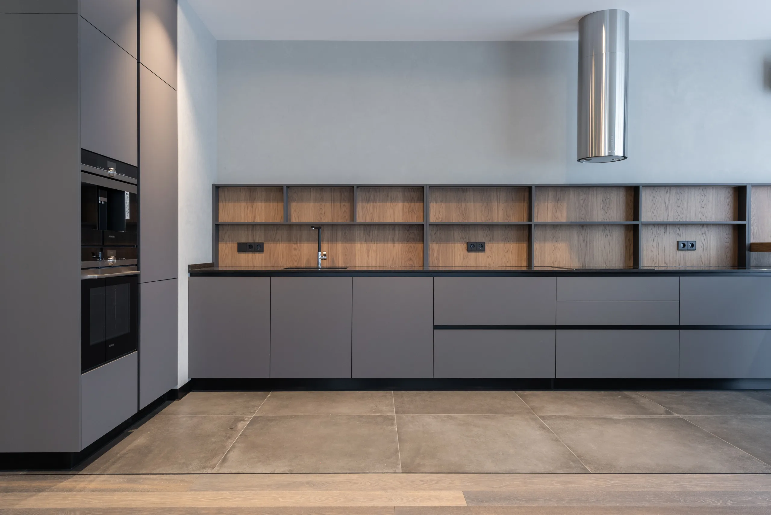 a kitchen with grey cabinets and wood shelves